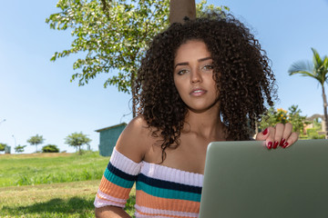Young black woman using laptop computer in park