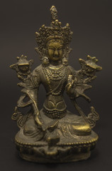 Fototapeta na wymiar Tibetan Buddhism: Green Tara brass sculpture isolated on dark background.