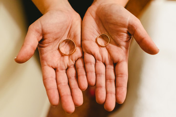 Newlywed rings shown in the hands of the bride and groom.