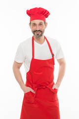 He is a fine hand at cooking. Senior cook with beard and moustache wearing bib apron. Mature chief cook in red cooking apron. Bearded mature man in chef hat and apron. Home cooking