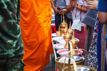 Laypeople make merits by giving food offerings to Buddhist monks going on daily alms round in morning at Mon Bridge, Sangkhlaburi, Kanchanaburi, Thailand. Traditional, Cultural Thai Travel and Tourism