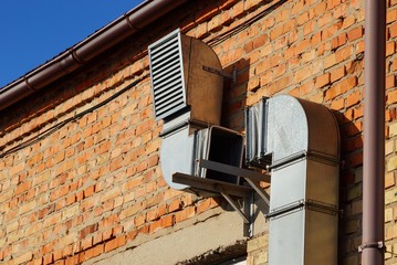 part of a gray long metal hood on a brown brick wall