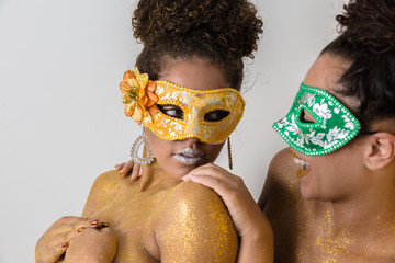 Two beautiful young women with their bodies painted in gold. Young African-American women dressed...