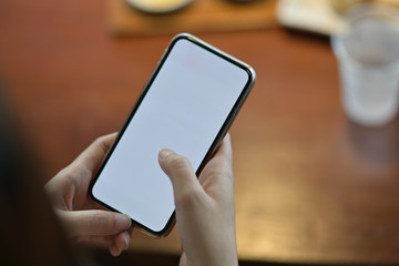 Cropped shot of female hands using mobile phone on desk