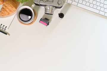 Office wood desk table with vintage camera, coffee, film, creative supplies and copy space