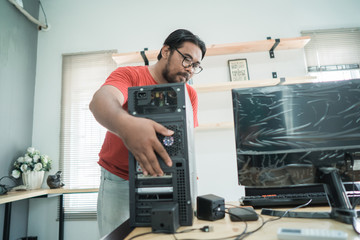 portrait of asian young man fix a problem with server of personal computer in office room