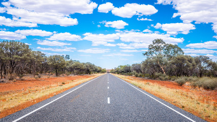 Straight road with white lines in middle of outback red centre Australia