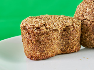 vegetarian bread made from germinated wheat and rye on a snow-white plate on a green background. healthy food. macrophotography
