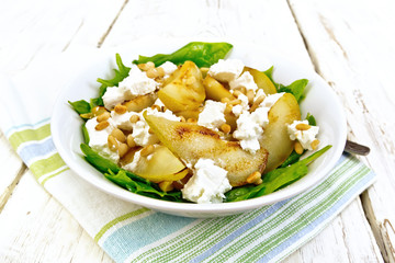 Salad from pear and spinach in dish on light board