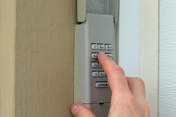 hand entering code on keypad - garage door opener - home security