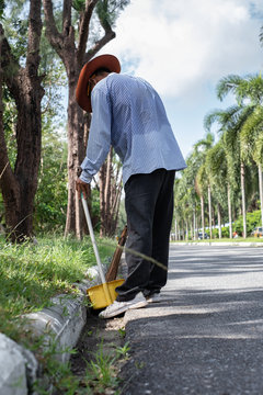 Cleaner rake garbages on street with bamboo broom.