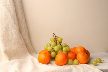 Composition of oranges, green grapes and linen cloth on wooden table. Still life of fresh fruits with empty place. © vaitekune