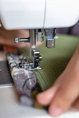 Tailoring Process - Close-up of women's hands behind her sewing on sewing machine.