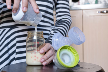 Young mother stock mother's milk into a bottle for baby drinking. Frozen Breast Milk.