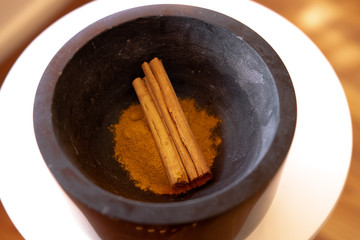 Cinnamon Quills and Ground Cinnamon in a charcoal gray dish. Mortar and pestle.
