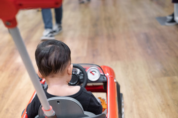 Little boy sit in big toy car, child enjoying shopping day with mother