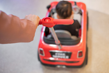 Close-up of parent's hand pushing big car toy for child