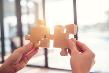 Closeup hand of woman connecting jigsaw puzzle with sunlight effect, Business solutions, success and strategy concept.