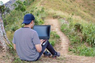 Man with laptop on the top of mountain, working during travel.