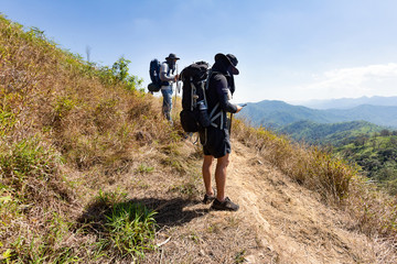 A pair of young man standing playing mobile phone and taking a rest after long walk of trekking. Mountain in Thailand, Khao Chang Puak in Kanchanaburi province.
