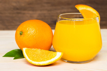 Navel orange juice and slices of orange with leaves on wooden background