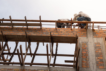 A team of workers working on the upper floor for under construction housing, with sunlight effect