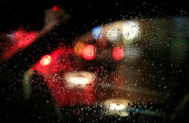 Lights of night city through the glass of the car with raindrops