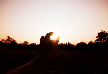 Hand on sky and sunrise in the evening.