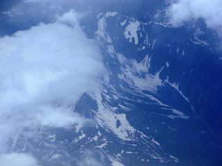 Mountains with snow and clouds, view from the plane.