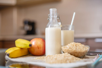 Rice milk in a glass Cup and fruit with scattered grains of rice on table in the kitchen. Healthy...
