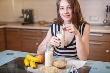 Happy young woman drinking organic rice milk holding glass Cup in her hands in kitchen. Diet healthy vegetarian product