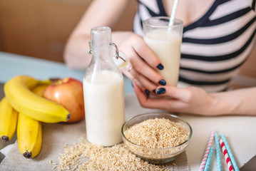 Girl drinking organic rice milk holding a glass Cup in hands in the kitchen. Top view. Diet healthy vegetarian product
