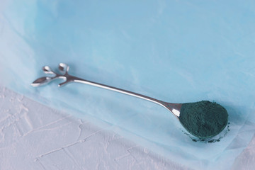Spirulina powder on a spoon close-up.