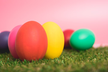 Fototapeta na wymiar Colorful Easter eggs clean on grass and pink background