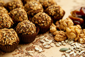 Round vegetarian sweets with ingredients from which they are made. Walnuts, sunflower seeds, dates are next to vegan vegetarian sweets.