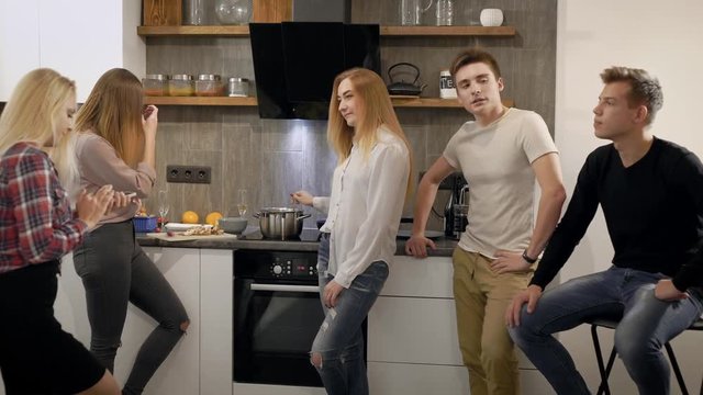 Two boys and three girls having small home party, cooking dinner together.