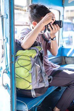 Young asian backpack traveler sit in old bus and take photography. Old local bus in Thailand. Trip to Thailand. Backpack travel concept.