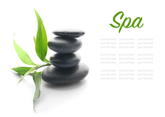 Stack of spa stones and green leaves on white background