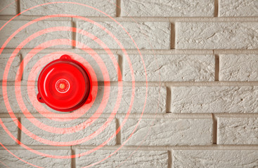 Modern alarm bell on brick wall indoors