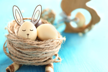 Decorative nest with chocolate Easter eggs on color wooden table