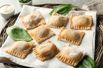 Uncooked ravioli on wicker tray