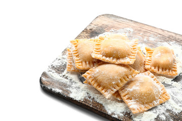 Wooden board with uncooked ravioli on white background
