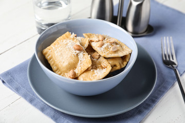Bowl with tasty ravioli on white table