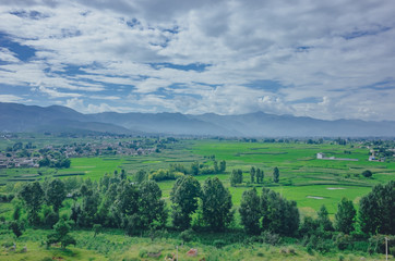 Fototapeta na wymiar Fields and mountains under sky and clouds in Dali, Yunnan, China