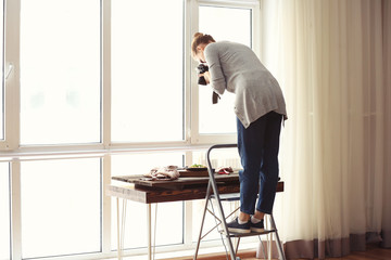 Young woman taking picture of food in professional studio