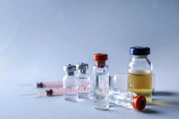 Syringes and ampules with vaccine against flu on light background