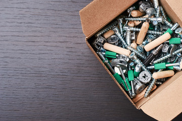 Open box with furniture assembly on a wooden background with copy space