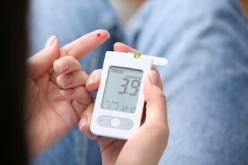 Diabetic woman using digital glucometer, closeup