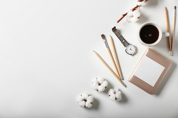 Composition with cup of coffee, stationery and watch on white background