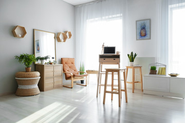 Stylish interior of room with laptop on high wooden table